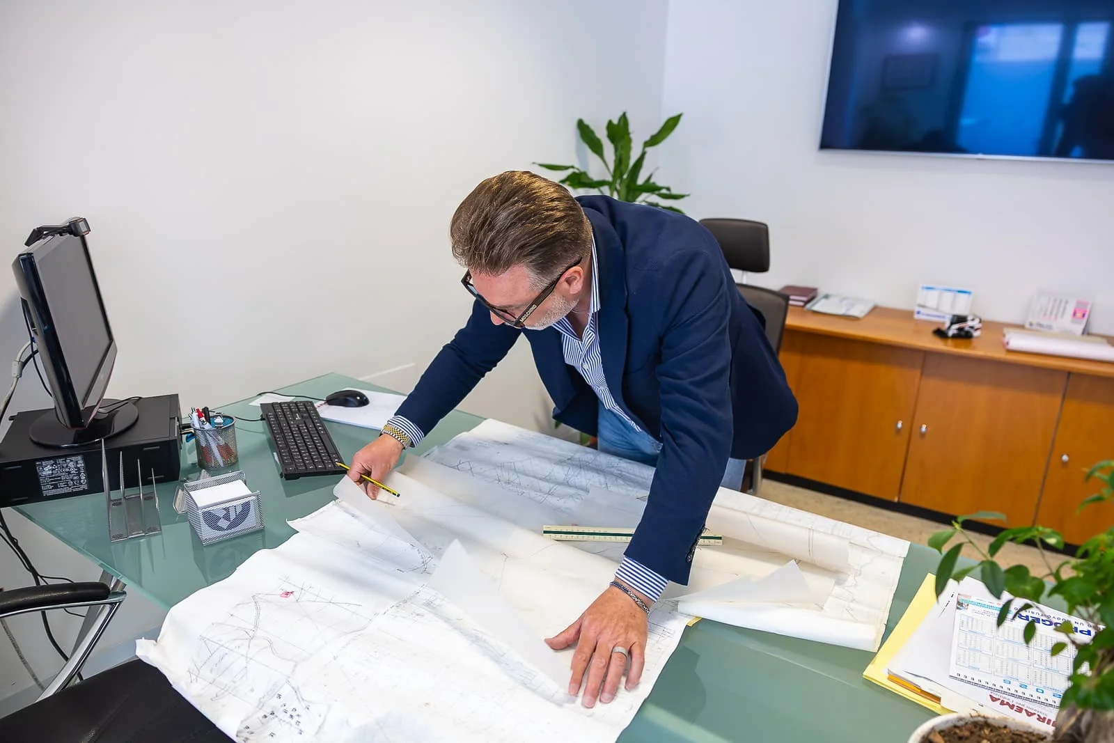Ingegnere nello studio tecnico di Edil Group mentre analizza e sviluppa una progettazione tecnica e rilievi topografici su una scrivania.